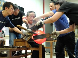 重く、高温のガラス加工には多くのスタッフを必要とし、息の合ったチームワークが要求される