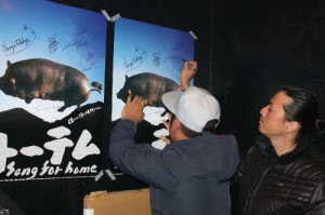 映画のポスターにサインをするメンバー