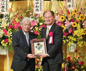 一般社團法人中華會館代表理事江夏良明（左），接受僑委會頒贈的「功在僑教」盾牌