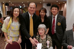 駐處長粘信士伉儷（後排左１、２）致贈８６歲以上華僑前輩禮券