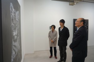 作品の持つ意味について、台湾文化センターの朱文清センター長（右）に説明するライアン・スーさん（中央）