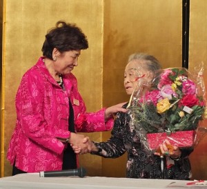 羅王明珠(右)於2015年3月8日出席婦女會慶祝活動,留日東京華僑婦女會會長吳淑娥特別致贈花束(本報資料照)