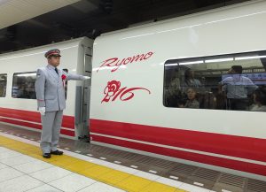 「猿(今年の干支)」マーク前で出発の合図をする下総駅長