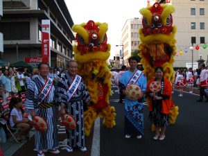 出発式で山形県日華親善協会からミニチュア花笠を受け取った鄭所長(右)
