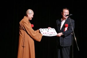 內閣府副大臣松本文明(右)收下主辦單位捐贈的熊本地震賑災款