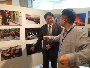 藩県長に写真の説明をするカメラマンの熊谷さん(右)