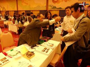 左)華視光學集團執行總裁黃福進為日本買家介紹視力回復眼鏡