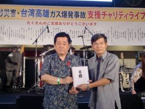 新垣直彥（左）代表主辦單位捐贈５０萬日幣，盼請駐處轉交給高雄市政府