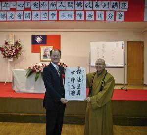 心定法師贈送駐橫濱辦事處處長粘信士（左）「信法至真，士紳高雅」的書帖一幅