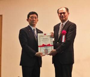 由駐橫濱辦事處處長粘信士（右）頒發當選證書，由會長羅鴻健代領