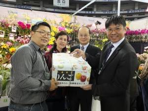 沈代表（右２）から贈られた青森のりんごを受け取る 台湾蘭花産銷発展協会の高紀清理事長（右１）と台大蘭園の頼永翔さん（左１）