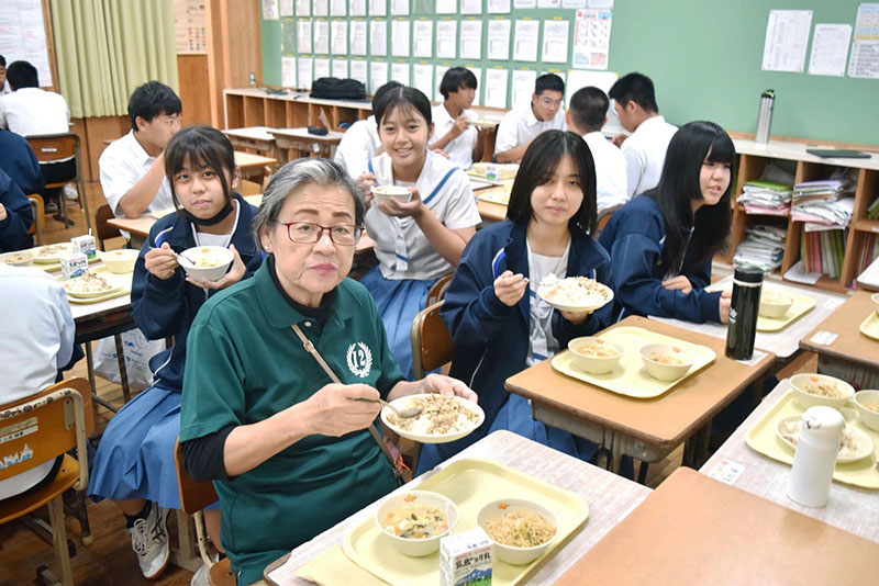 琉球華僑總會宮古支部長羽地芳子(左,綠衣)與學生共享台灣料理營養午餐